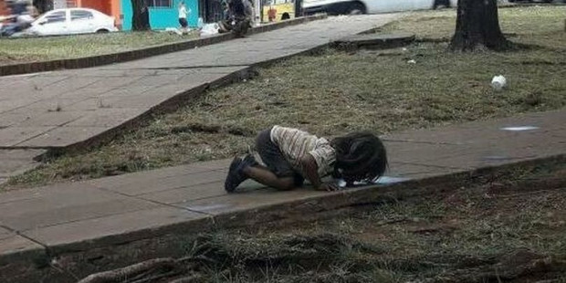 Tiny girl goes down on hands and knees to lick water from dirty puddle in picture which shocked Arge
