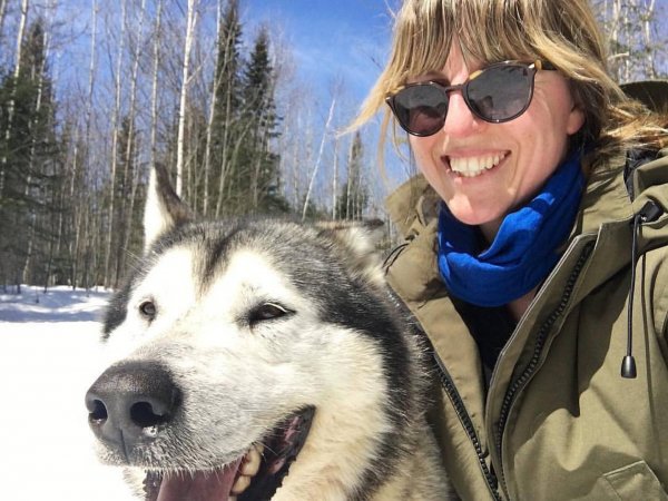 Claire Nelson poses with a husky dog while sledding in Canada